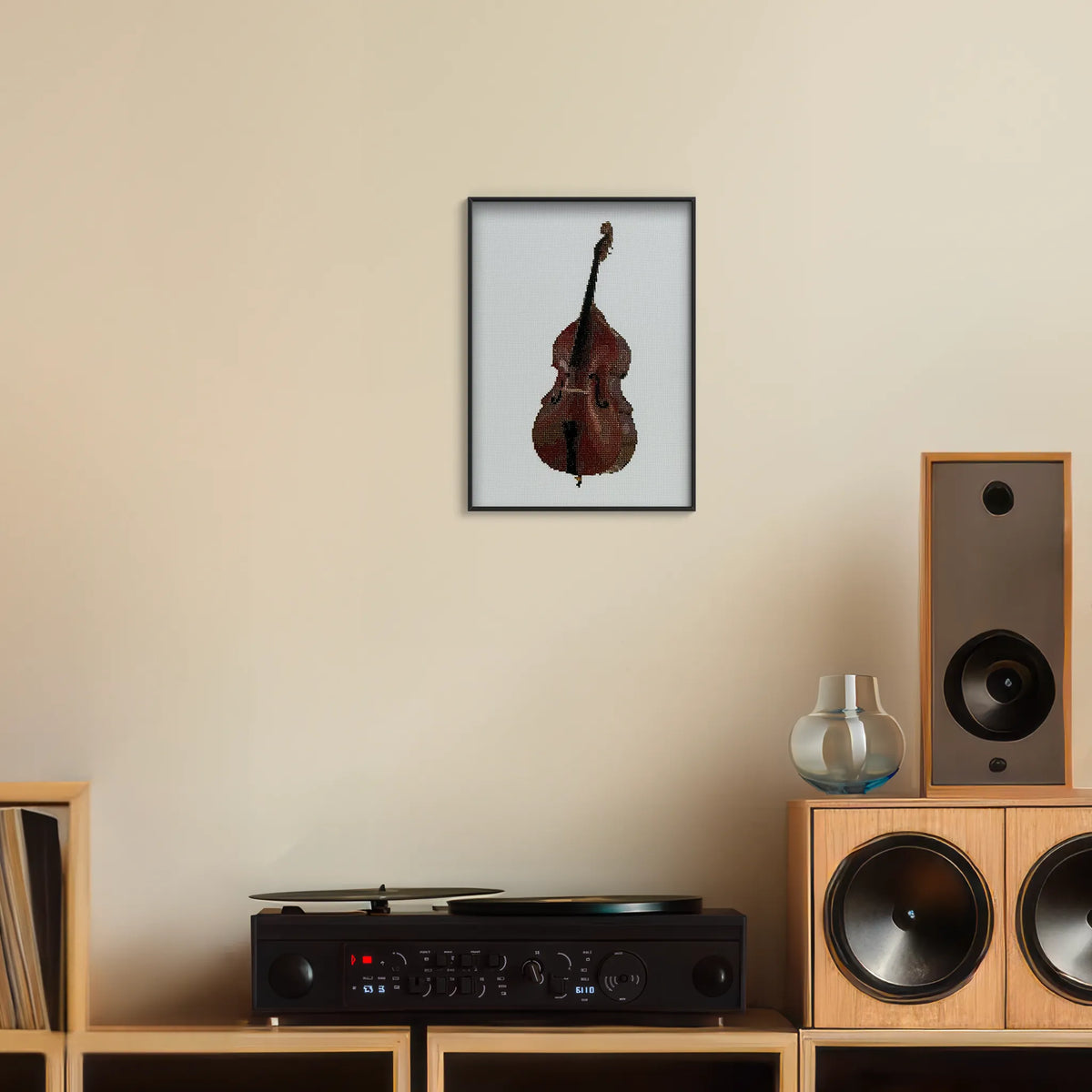 A4 print of the original embroidery design of a double bass framed and hung up on a wall above a record player
