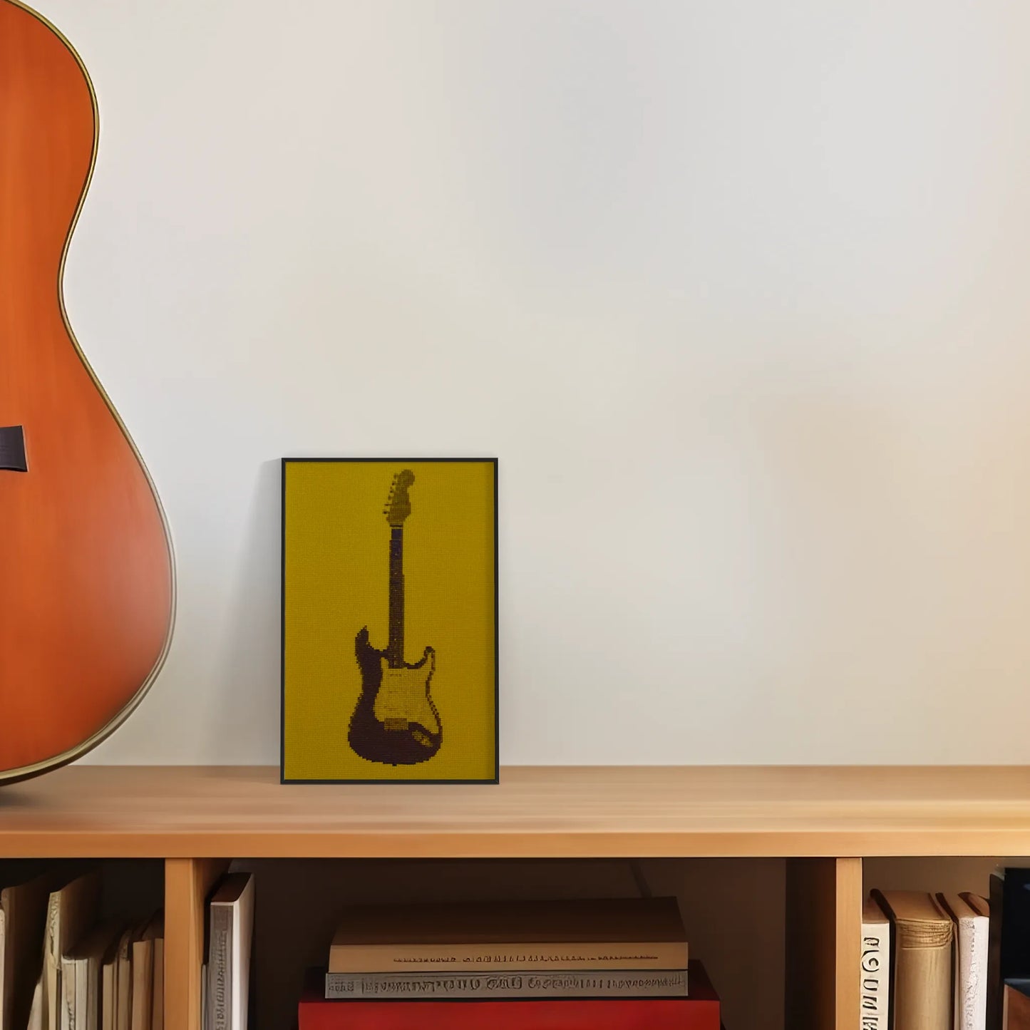 colourful postcard of the original embroidery design of a fender strat framed and leaning against a wall next to a guitar