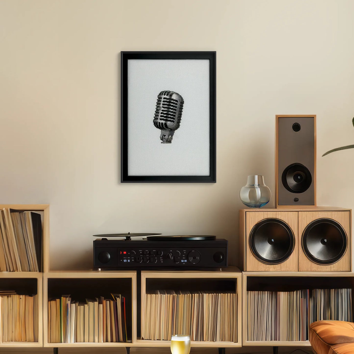 Framed hand-stitched retro mic on white fabric hung up on a wall above a record player