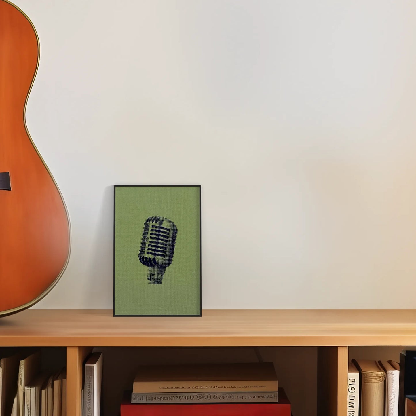 colourful postcard of the original embroidery design of a vintage mic framed and leaning against a wall next to a guitar