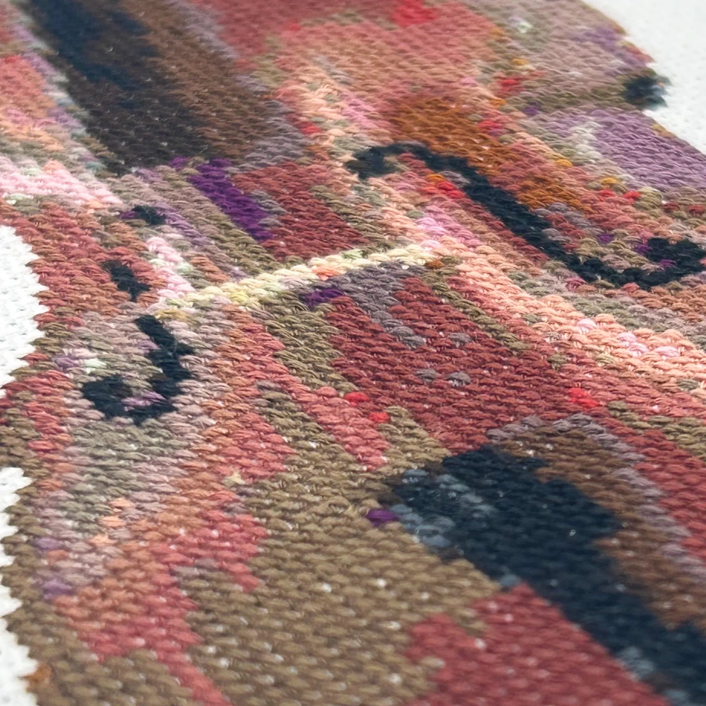 Close up of the stitches of an embroidered double bass on white fabric