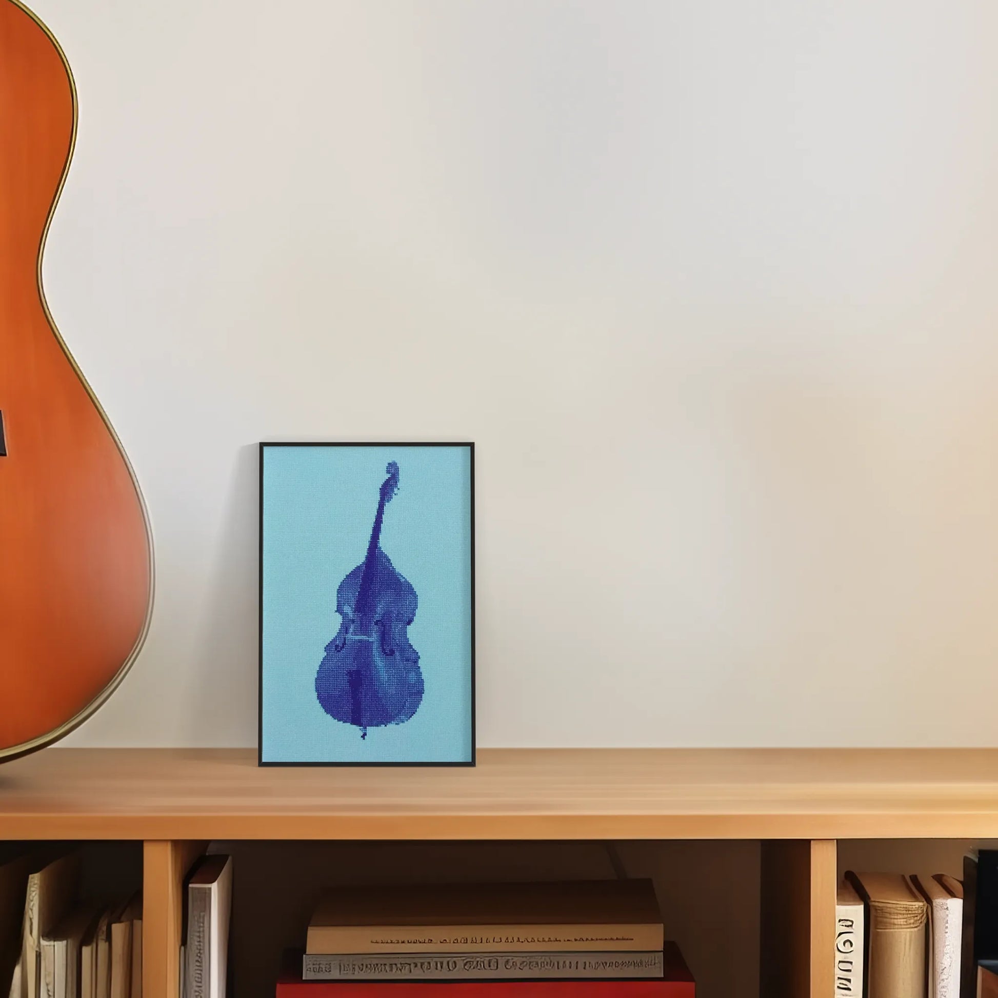 colourful postcard of the double bass original embroidery design framed and leaning against a wall on top of a desk