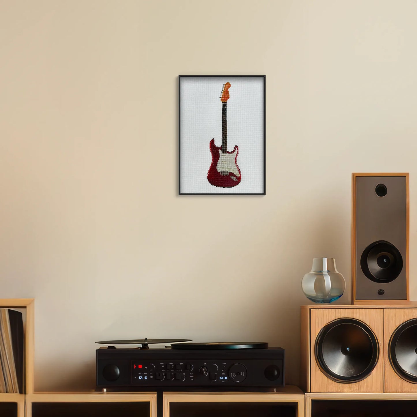 A4 print of the original embroidery design of a fender strat framed and hung up on a wall above a record player