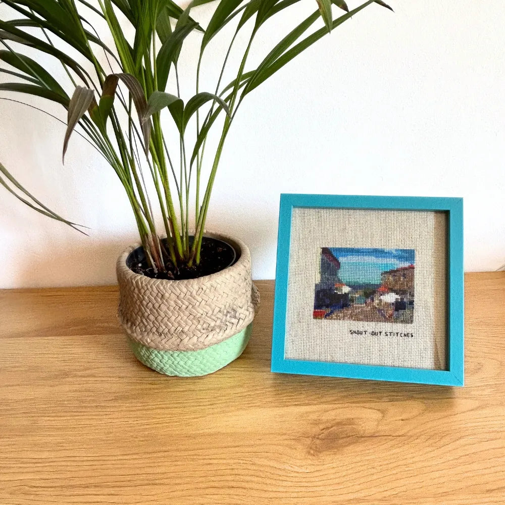 Framed Illa de Ons cross-stitch in a blue square frame