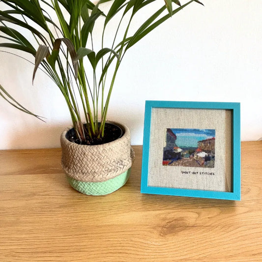 Framed Illa de Ons cross-stitch in a blue square frame