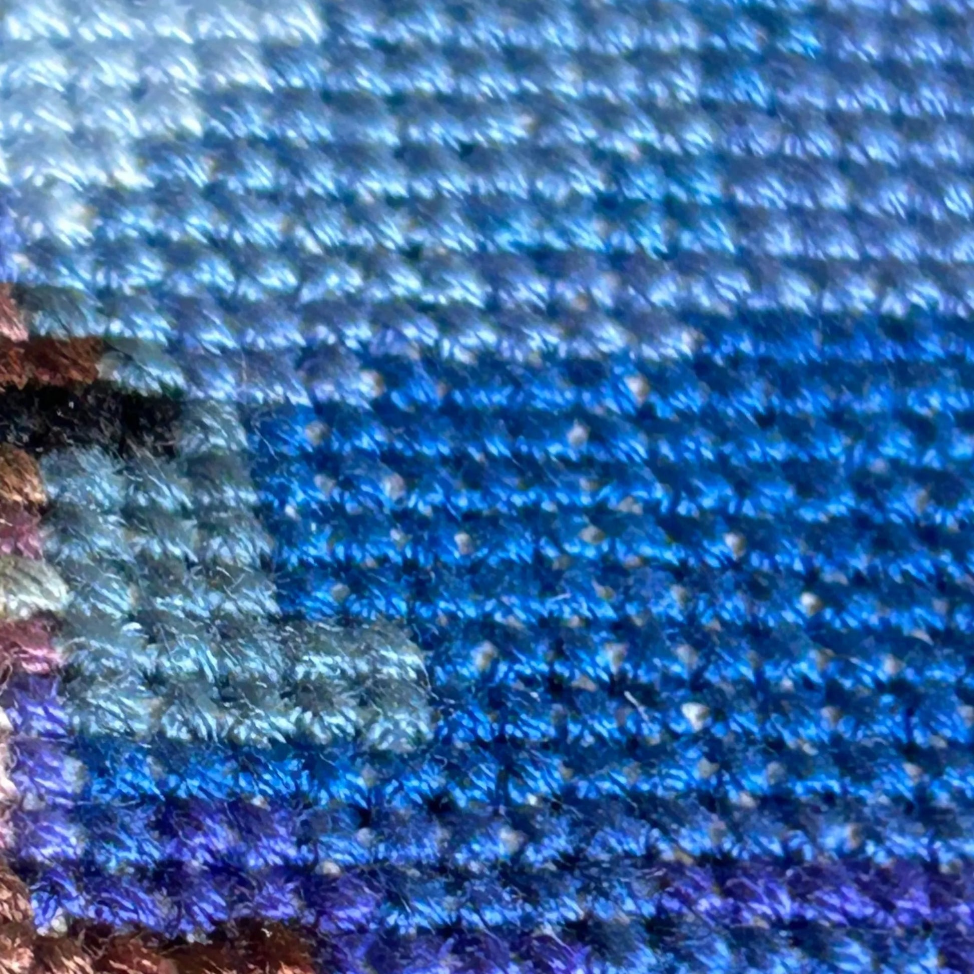 Close up of the different blue shades of thread used in the sky of the scenic evening cross stitch of Gijon, Asturias, Spain.