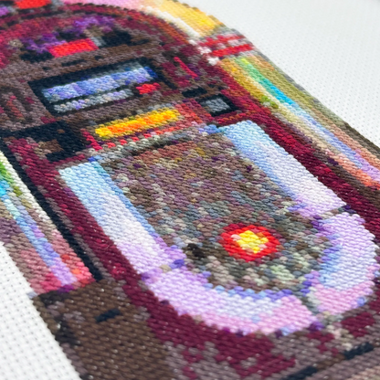 Close-up of cross-stitch of a retro jukebox on white fabric