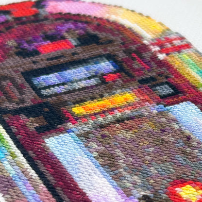 Close-up of cross-stitch of a retro jukebox on white fabric