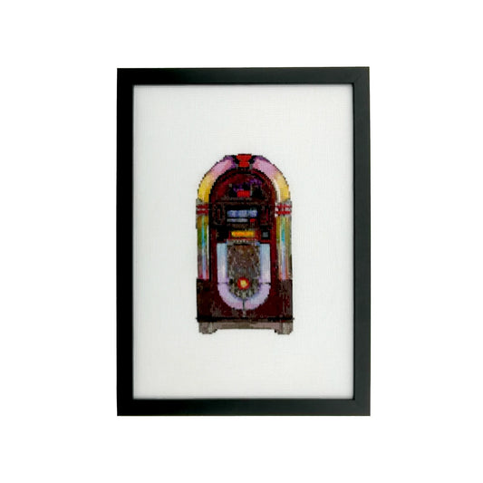 Framed cross stitch artwork of a vintage jukebox on white fabric