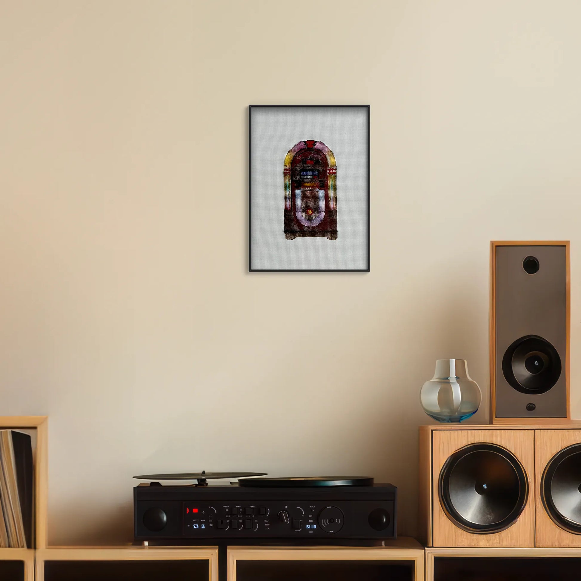 A4 print of the original embroidery design of a retro jukebox framed and hung up on a wall above a record player