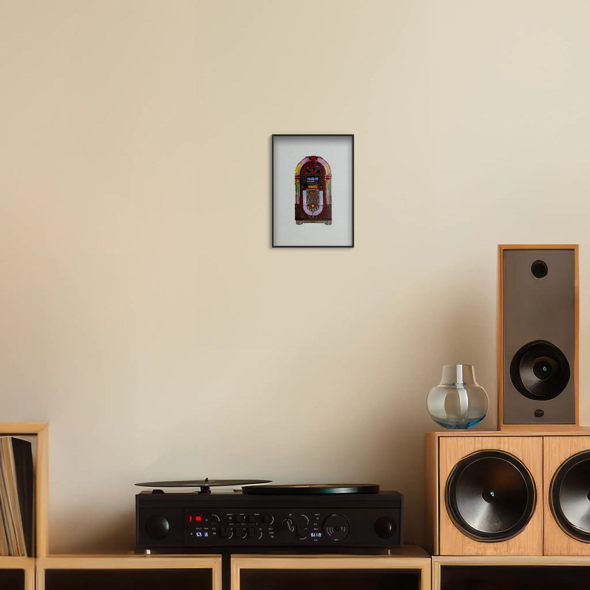 A5 print of the original embroidery design of a vintage jukebox framed and hung up on a wall above a record player