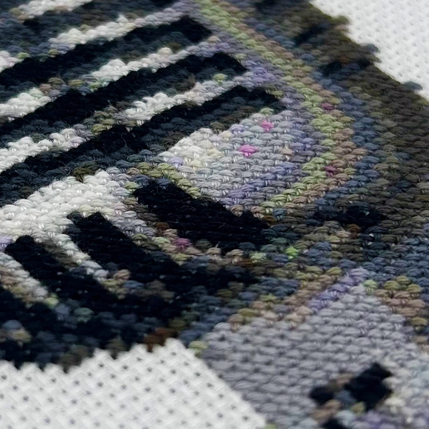 Cross-stitch details of a retro mic on white fabric