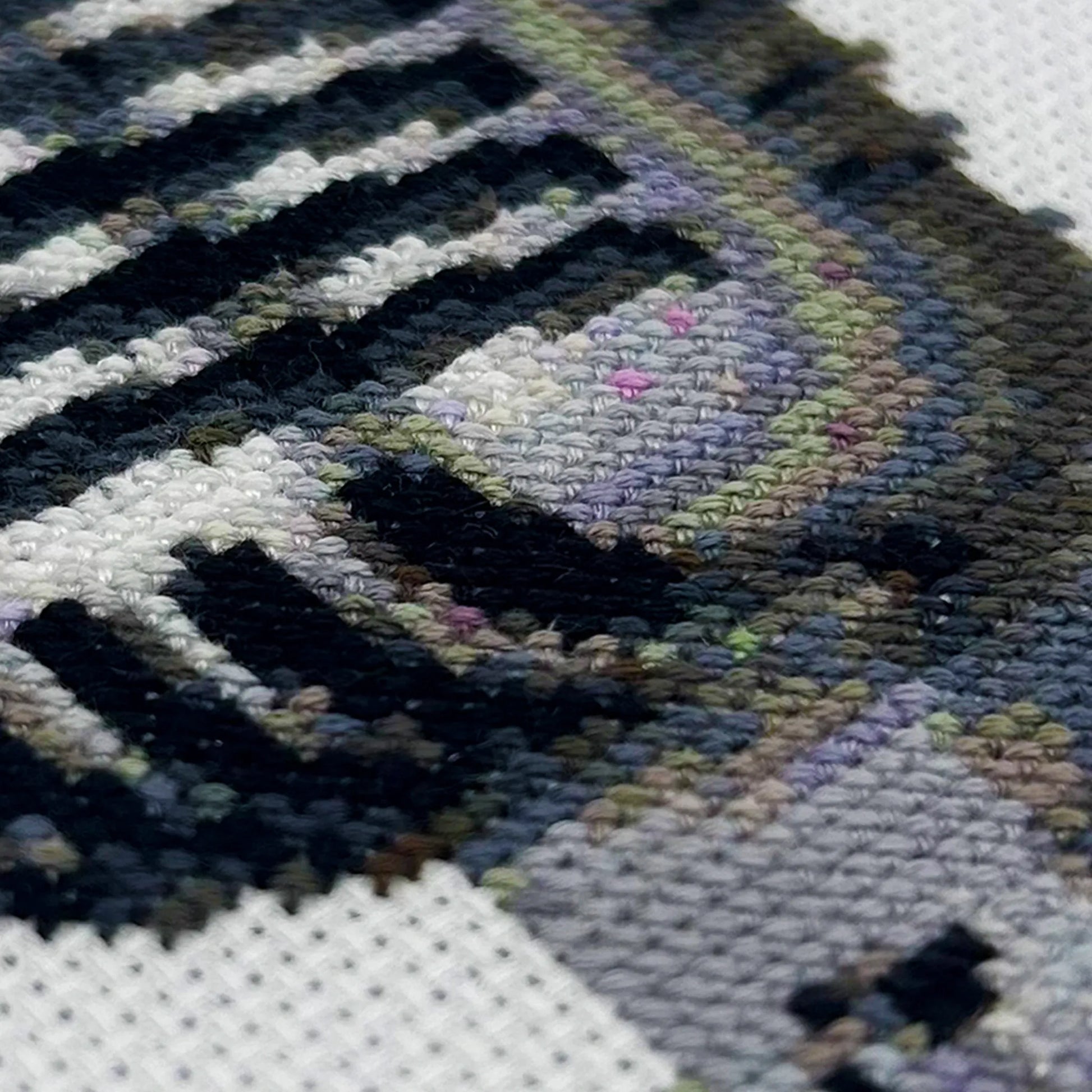 Cross-stitch details of a retro mic on white fabric
