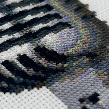 Cross-stitch details of a retro mic on white fabric