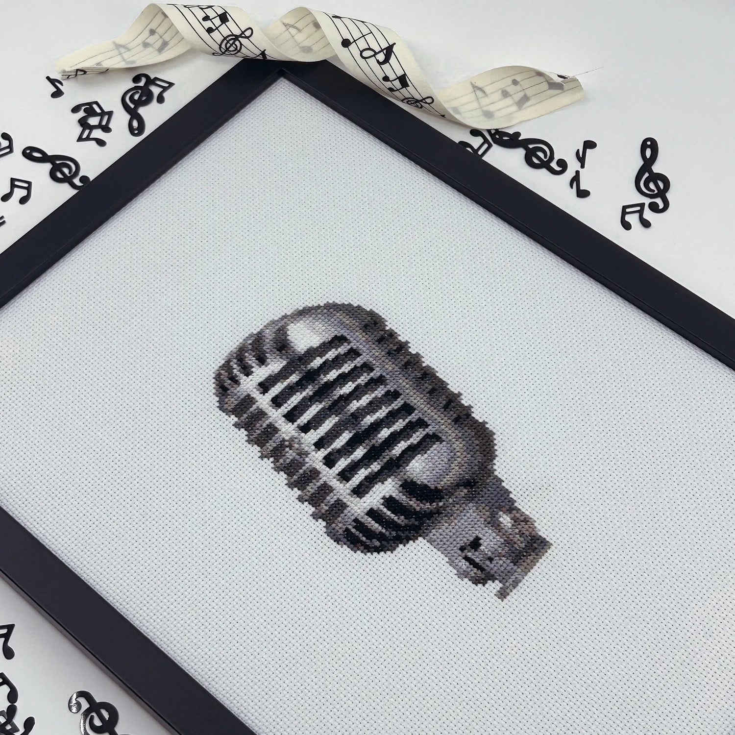 Framed hand embroidered artwork of a retro mic on white aida fabric.